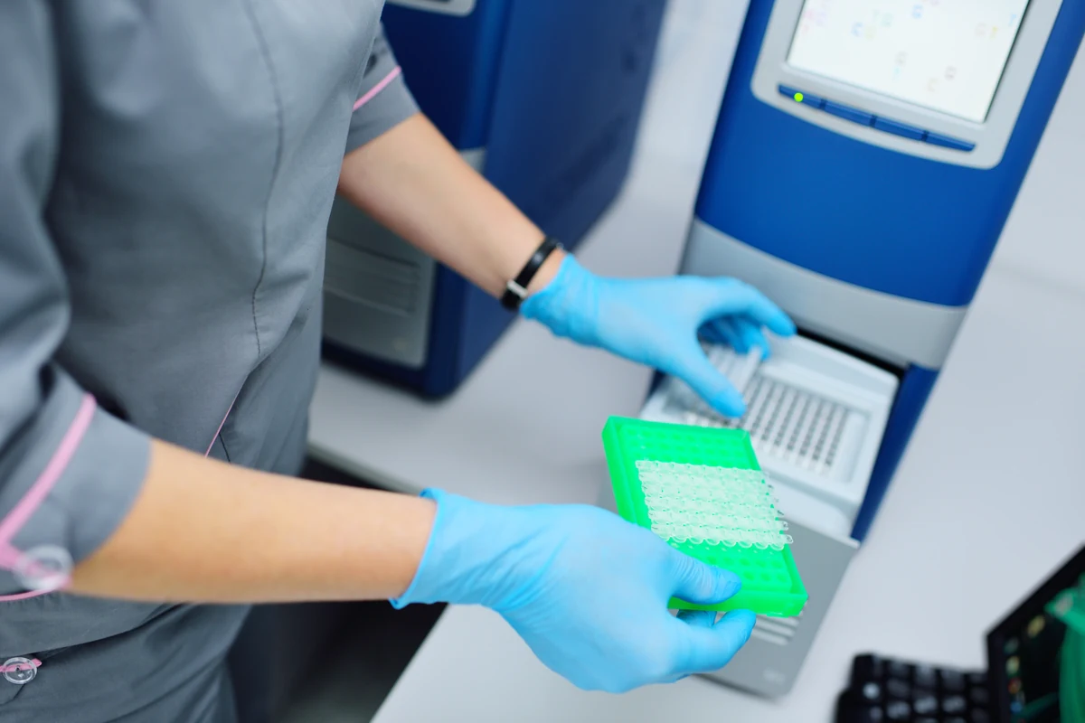 Tecnico di laboratorio che carica una piastra PCR in uno strumento